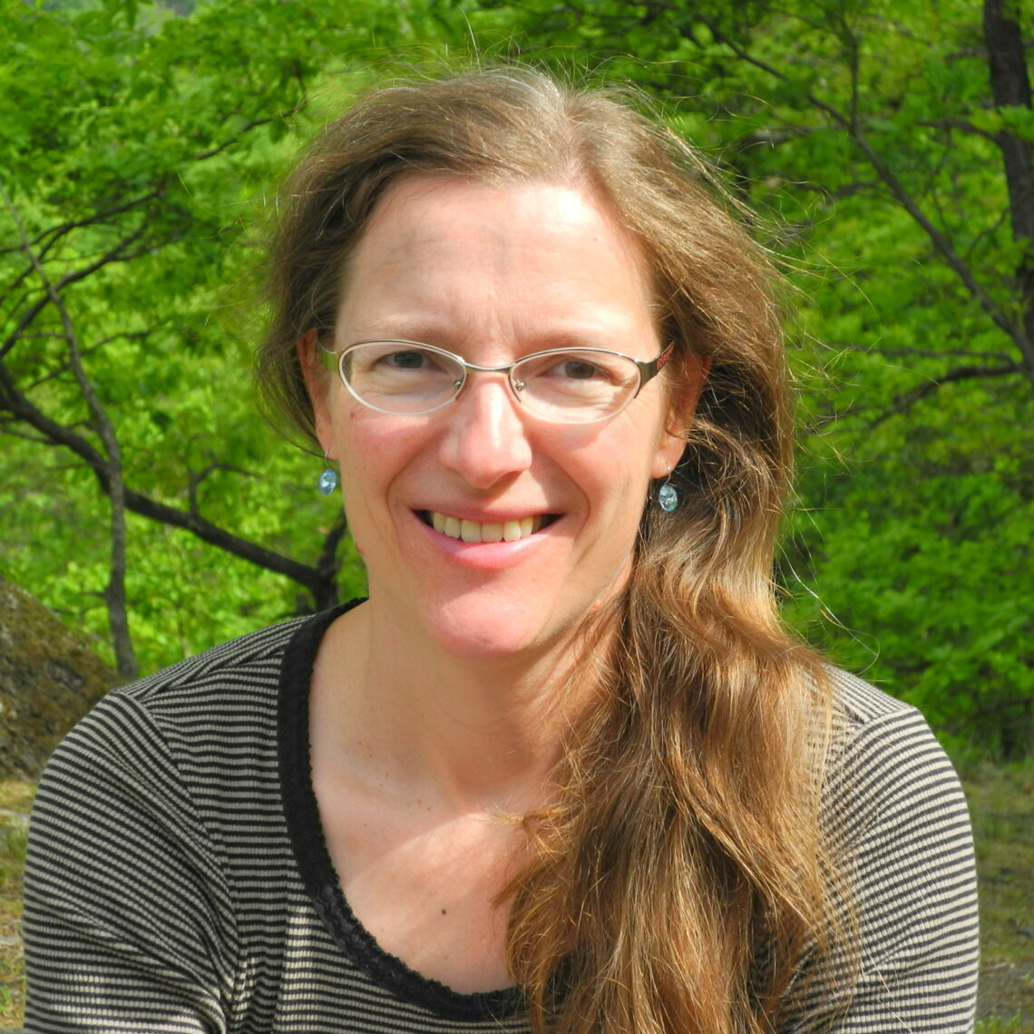 A woman wearing glasses and smiling at the camera