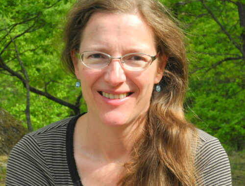 A woman wearing glasses and smiling at the camera